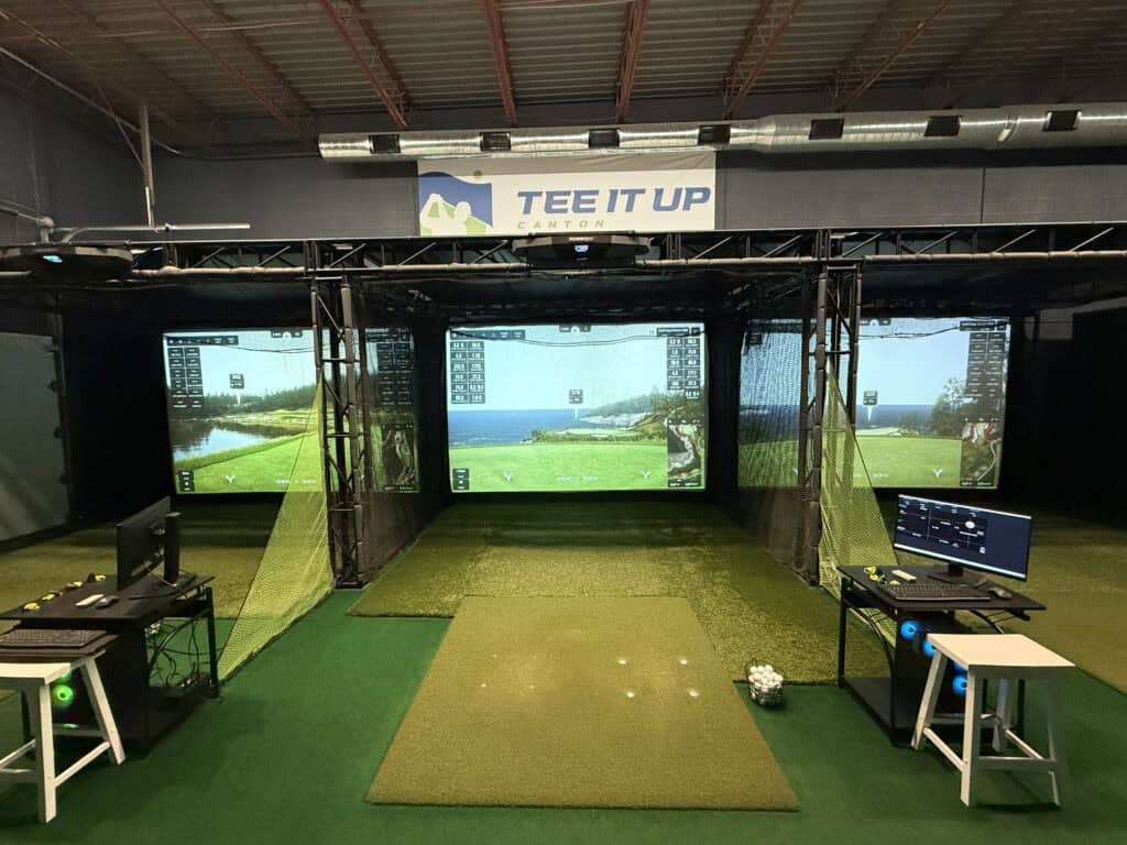 tee it up canton's interior featuring three golfing bays with courses displayed